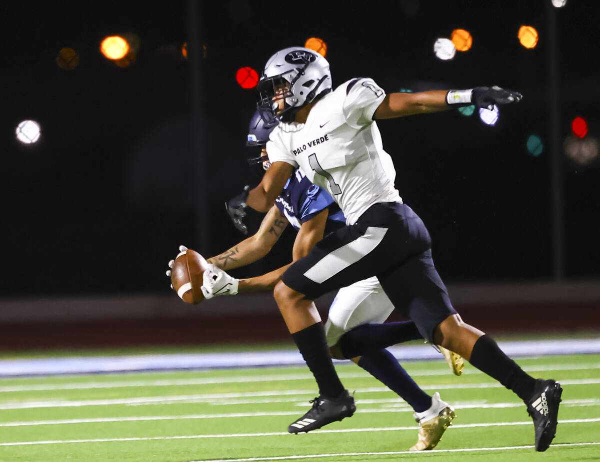 Canyon Springs' Lackawanna Caston (12) pulls in a pass under pressure from Palo Verde's Sammy G ...
