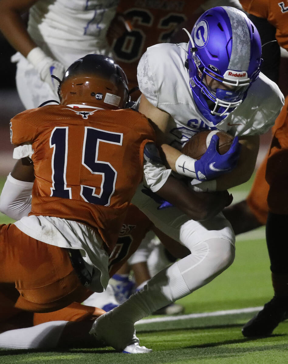 Bishop Gorman High School's Cam Gray (33) is tackled by Legacy High School's Micah Mcgirt (15) ...