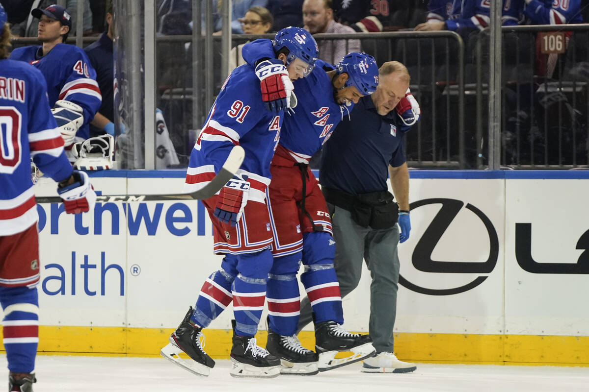 New York Rangers' Sammy Blais (91) and a trainer help Ryan Reaves off the ice after he was inju ...