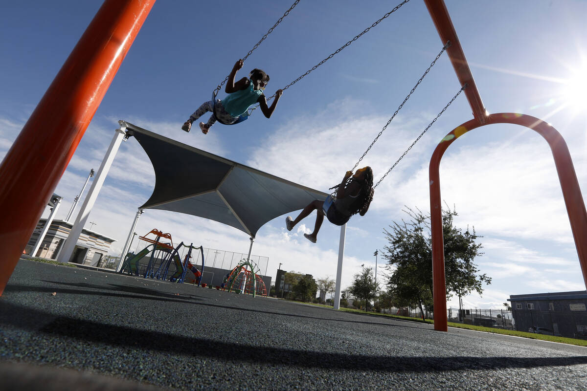 Juju Lowe , 7 of Las Vegas, left and her sister Oddy Tweedie, 11, play on swings at Baker Park, ...
