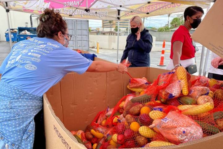 A volunteer at the Just One Project grabs a bag of produce during United Way of Southern Nevada ...