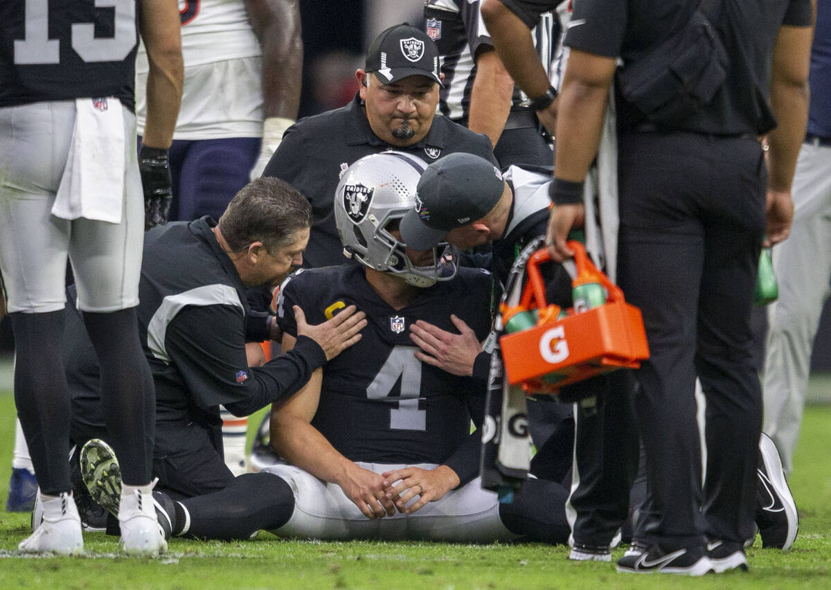 Raiders quarterback Derek Carr (4) has his shoulder looked at after getting hurt on a quarterba ...