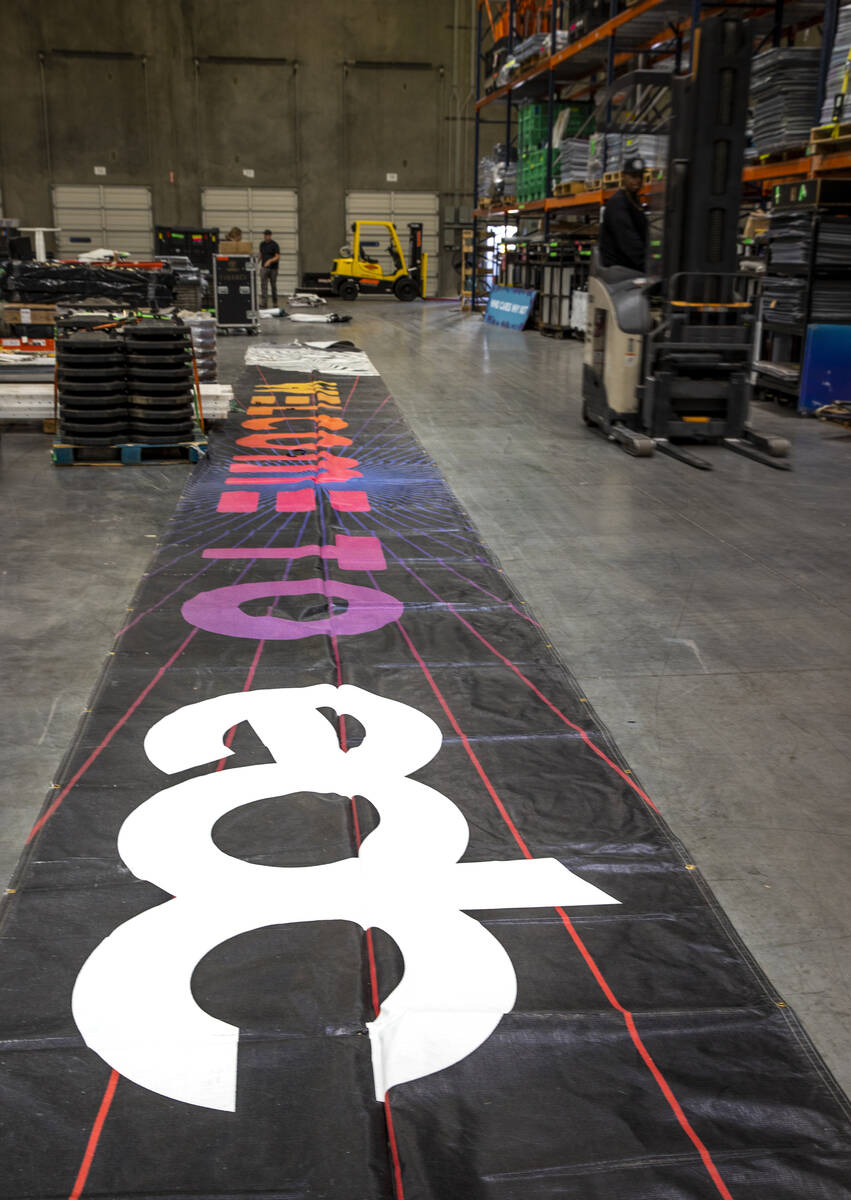 A large banner is unfurled within the Electric Daisy Carnival warehouse as they prepare for com ...