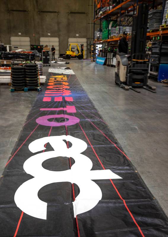 A large banner is unfurled within the Electric Daisy Carnival warehouse as they prepare for com ...