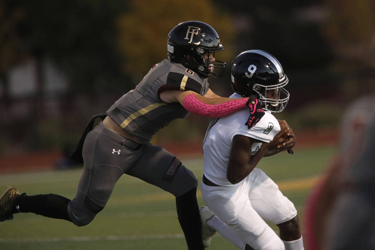 Faith Lutheran School's Blake Driscoll (6) tries to stop Desert Pines High School's Michael Kea ...