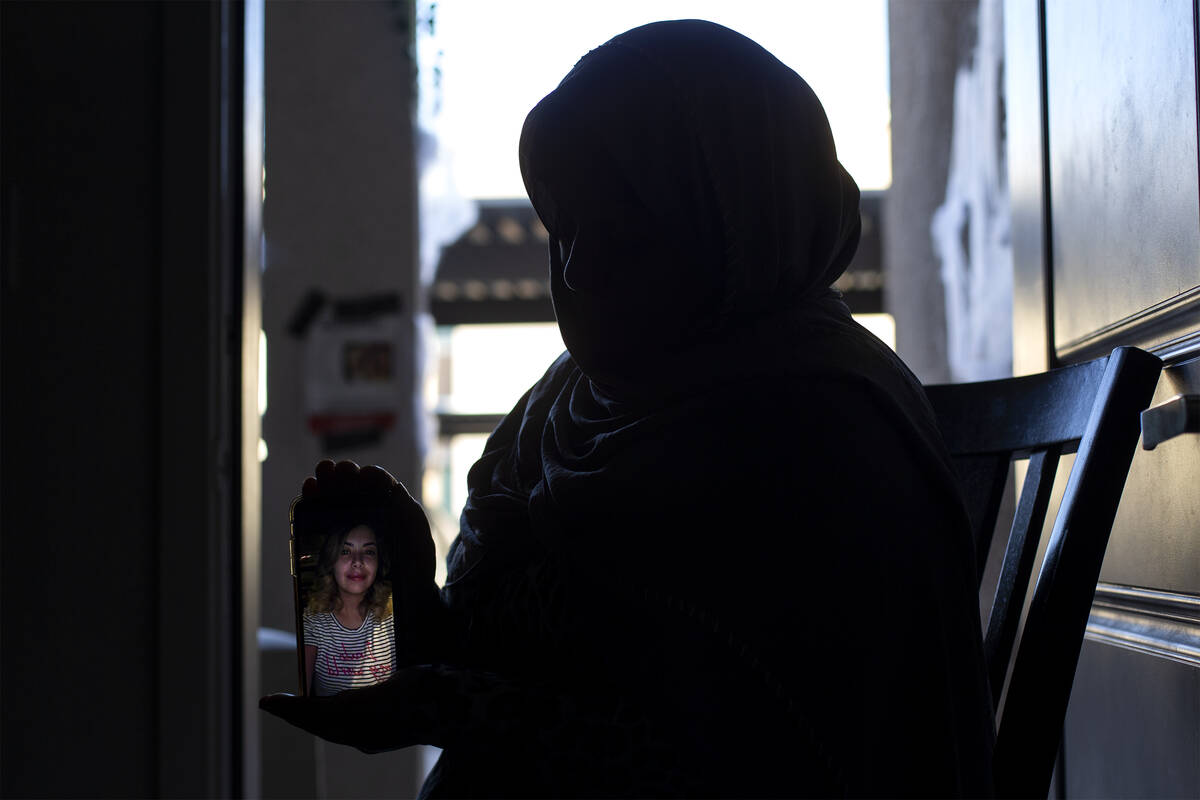 Mrs. Hejji, mother of Jawaher Hejji, holds a photograph of her late daughter at her daughter Ma ...