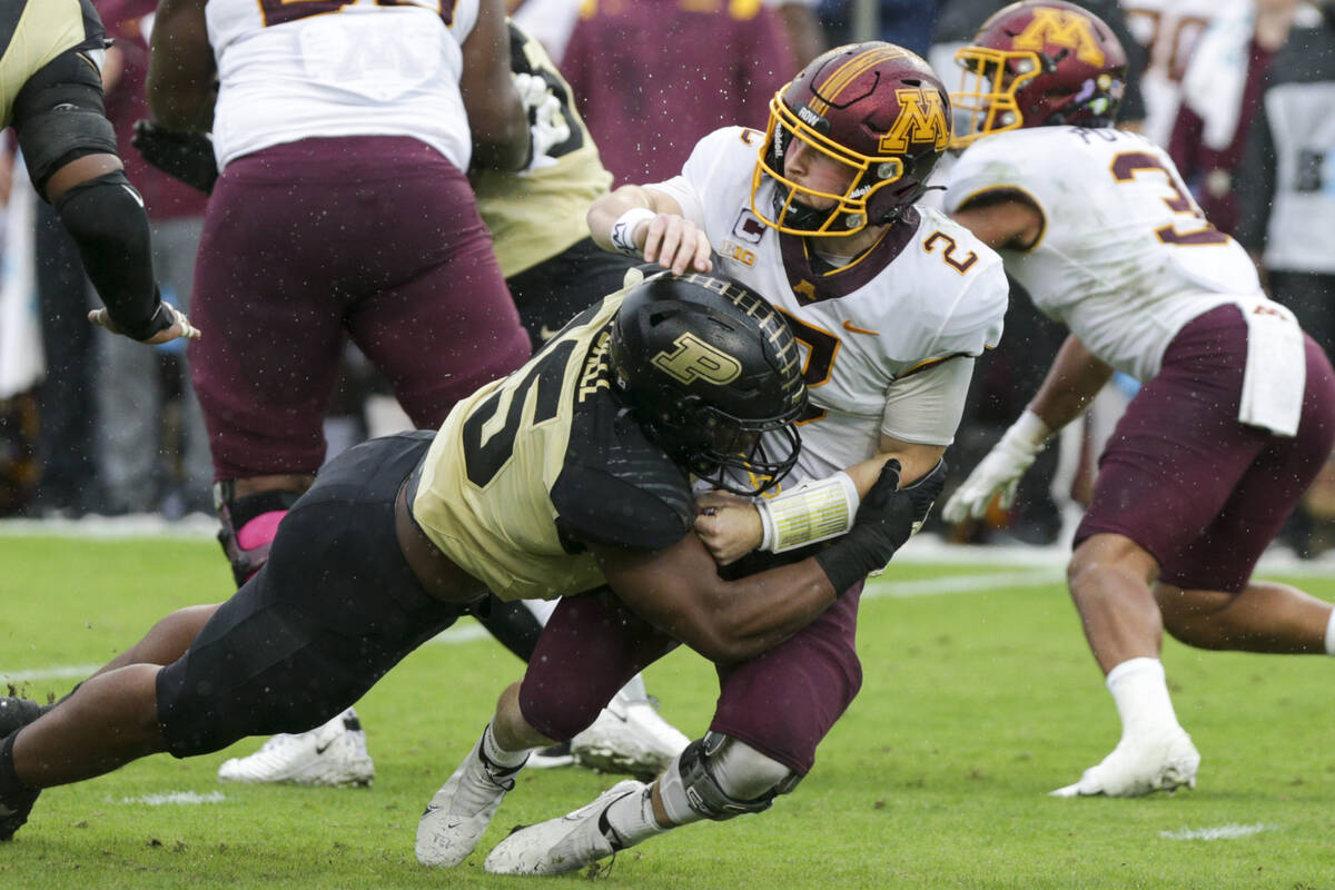 Purdue defensive end George Karlaftis (5) tackles Minnesota quarterback Tanner Morgan (2) durin ...