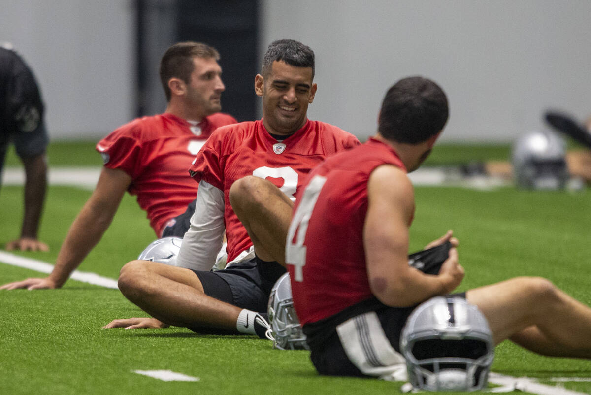 Raiders quarterback Marcus Mariota (8) and Raiders quarterback Derek Carr (4) share a laugh dur ...