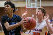 Desert Pines freshman Milos Uzan (12) drives past Bishop Gorman senior guard Noah Taitz (20) in ...