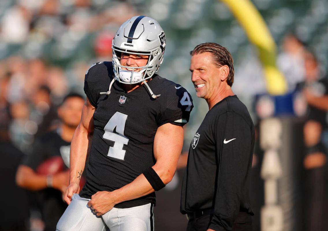 Oakland Raiders quarterback Derek Carr (4) talks with offensive coordinator Greg Olson before a ...
