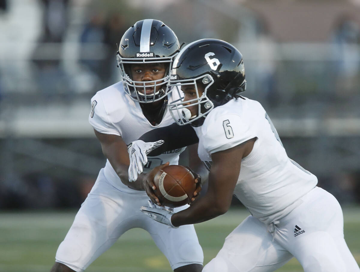 Desert Pines High School's Michael Kearns (9) hands off to Desert Pines High School's Ferrari B ...