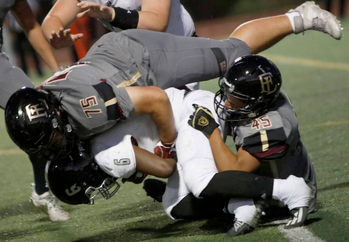 Desert Pines High School's Ferrari Busby (6) is tackled by Faith Lutheran School's Tobyas Spott ...
