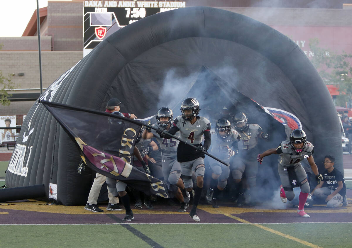 Faith Lutheran School's players run out to the field before a football game against Desert Pine ...