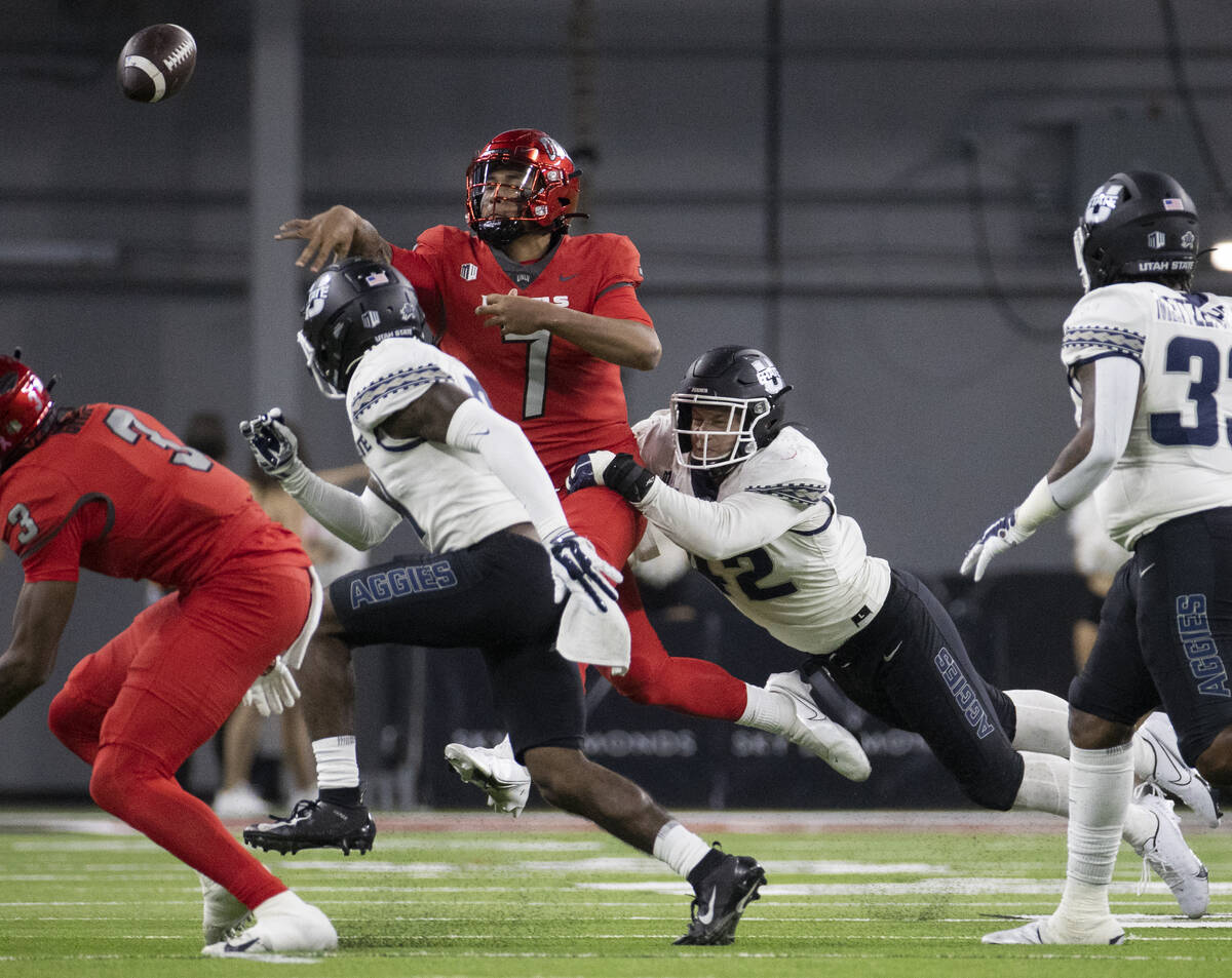 UNLV Rebels quarterback Cameron Friel (7) just gets the ball away with pressure from Utah State ...