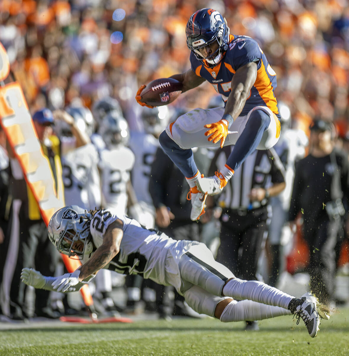 Denver Broncos running back Javonte Williams (33) jumps over the Raiders' free safety Trevon Mo ...