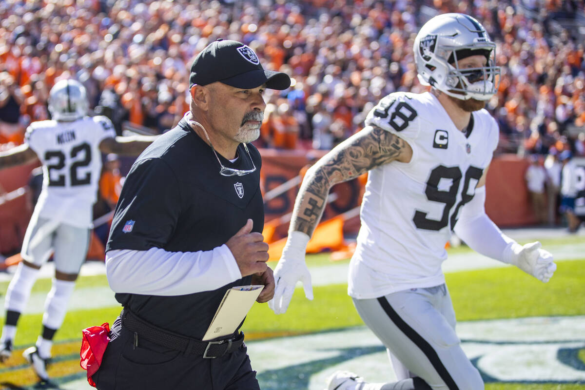 Raiders' interim head coach Rich Bisaccia runs out onto the field beside defensive end Maxx Cro ...
