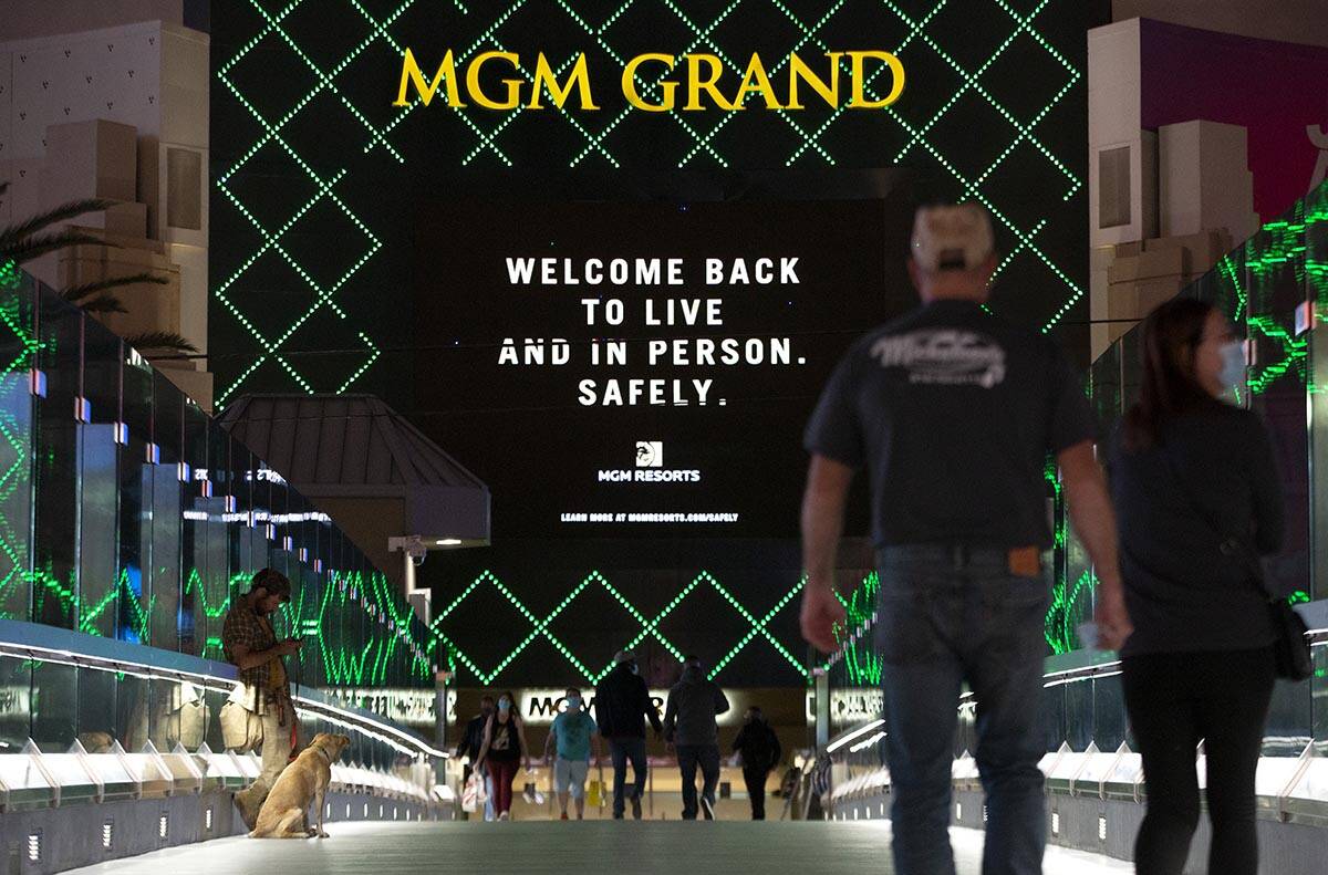 An MGM Grand marquee references coronavirus as visitors cross a pedestrian bridge on Monday, No ...