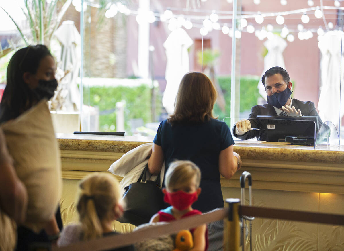 Guest service representatives wear protective masks and gloves while checking people in at TI o ...