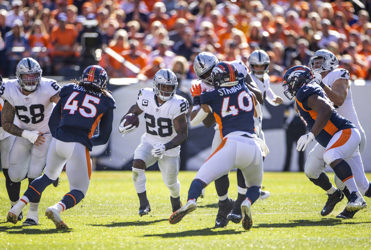 Raiders running back Josh Jacobs (28) looks to a hole in the offensive line versus the Denver B ...