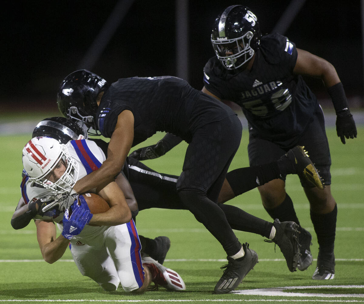 Liberty's Brody Clark (22) is tackled by Desert Pines' Landon Mccomber (25) and Leonard Ramos ( ...