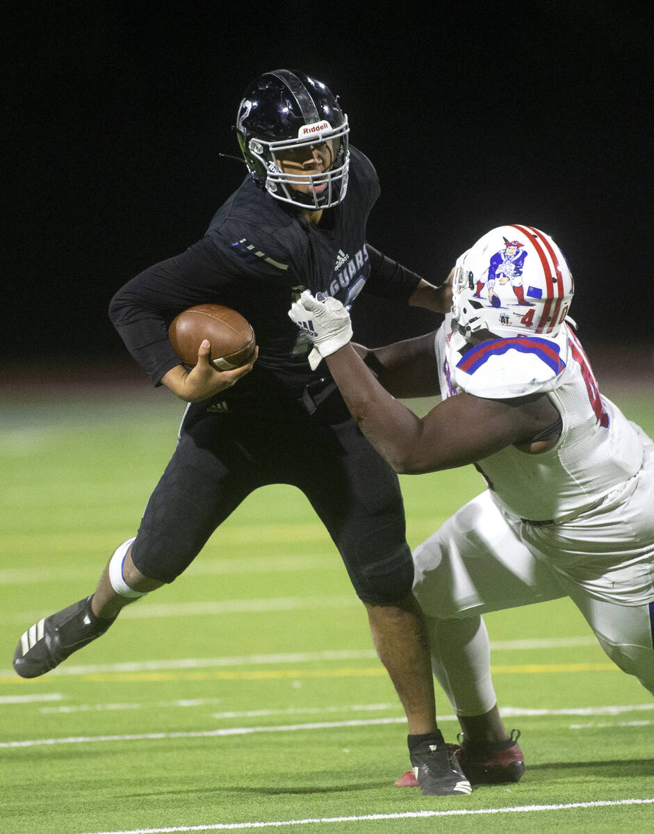 Desert Pines' Eddie Sandoval (12) attempts to evade a tackle from Liberty's Sir Mells (40) duri ...