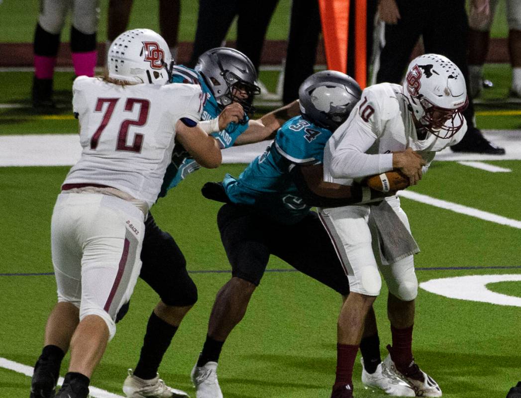 Desert Oasis quarterback Tyler Stott (10) sucked by Silverado High’s fullback Demetrius ...