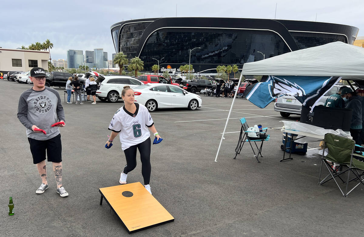 Philadelphia Eagles fan Caroline Miller of Miami plays cornhole with Raiders fan Randy Stober o ...