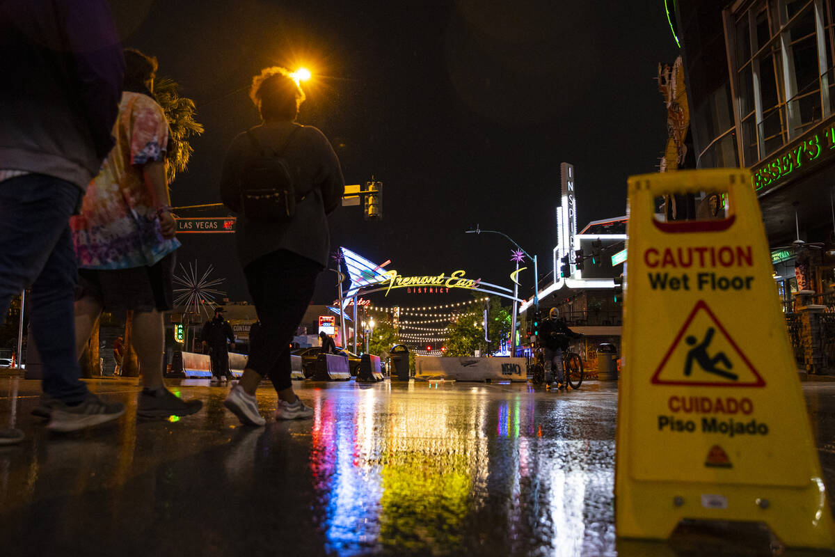 People walk towards Fremont East as rain comes down in downtown Las Vegas on Monday, Oct. 25, 2 ...