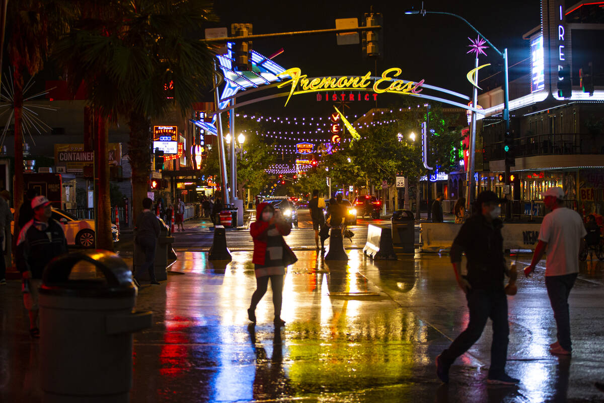 People walk around Fremont Street as rain comes down in downtown Las Vegas on Monday, Oct. 25, ...