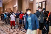 Players in masks wait in line to register for events on the first day of the World Series of Po ...
