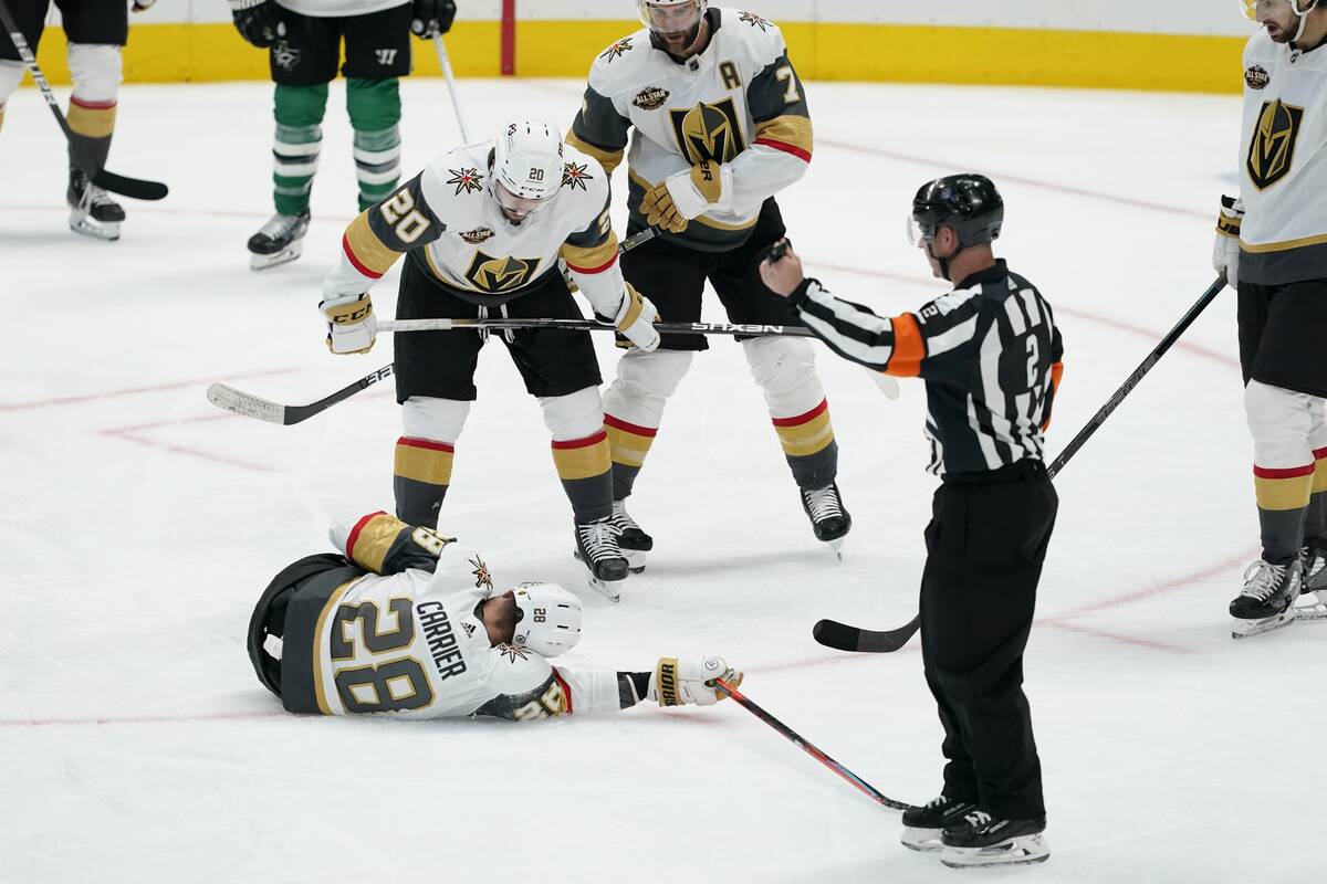 Vegas Golden Knights' William Carrier (28) is checked on by Chandler Stephenson (20), Alex Piet ...