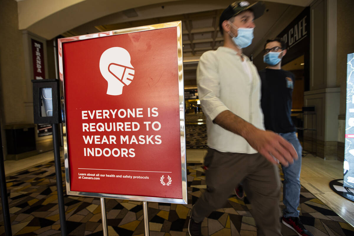 People walk by a sign about indoor mask wearing at the World Series of Poker at the Rio in Las ...