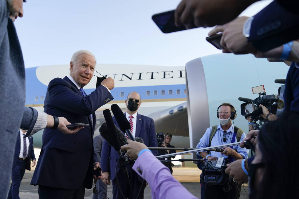 President Joe Biden removes his face mask as he speaks to members of the media before boarding ...