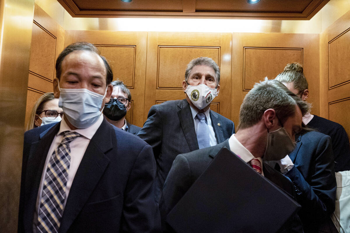 Sen. Joe Manchin, D-W.Va., center, and Sen. Kyrsten Sinema, D-Ariz., far left, board an elevato ...