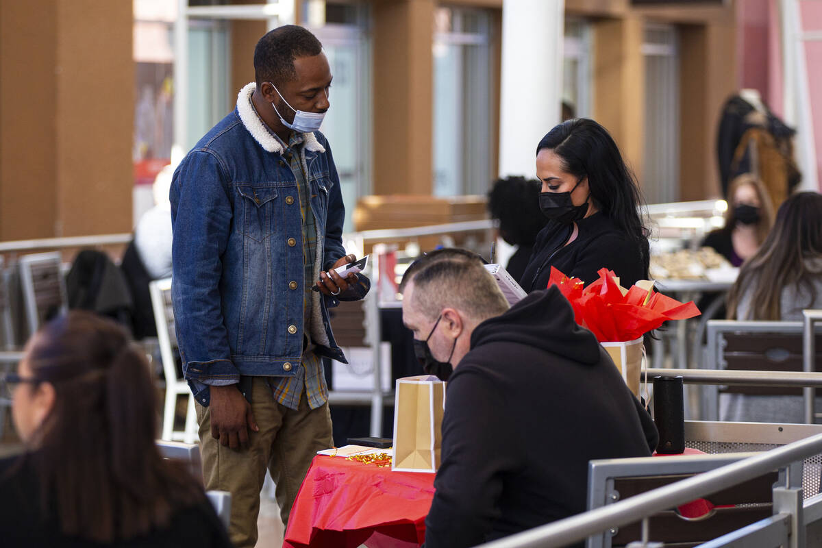 Sergio Pinto, of Las Vegas, talks with a representative from Michael Kors during a hiring fair ...