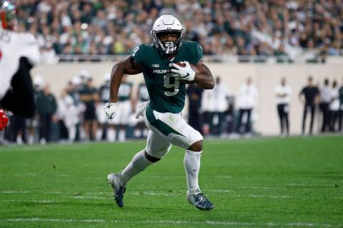 Michigan State moving  backmost  Kenneth Walker III runs for a touchdown during an NCAA assemblage   ft  ...