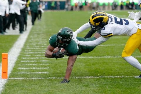 Michigan State's Kenneth Walker III, left, dives implicit    the extremity   enactment     for a touchdown against Mic ...