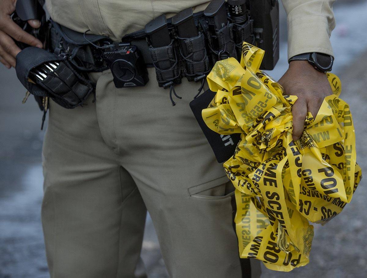 A Metro officer with a handful of crime scene tape as they conduct a homicide investigation at ...
