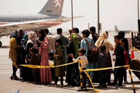 Civilians prepare to board a plane during an evacuation at Hamid Karzai International Airport, ...