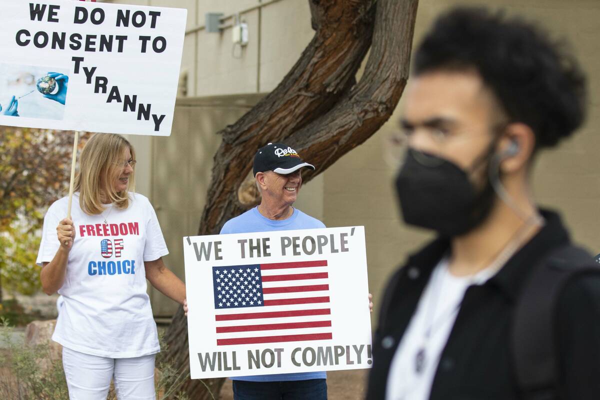 A UNLV student walks past Julie Williams and her husband Terry, both of Henderson, as they prot ...
