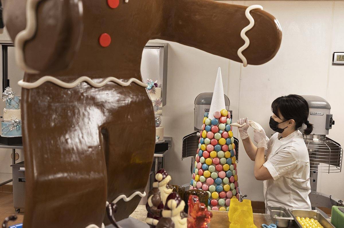 Assistant executive pastry chef Sunny Lee uses icing to apply macaroons to a decorative cone wh ...