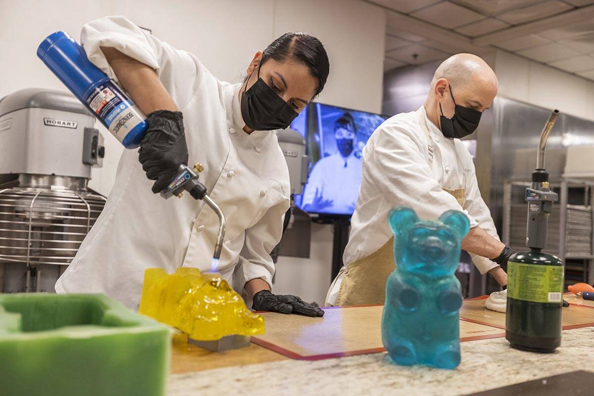 Assistant pastry chef Andrea Madrid, left, warms up a large decorative gummy bear while executi ...