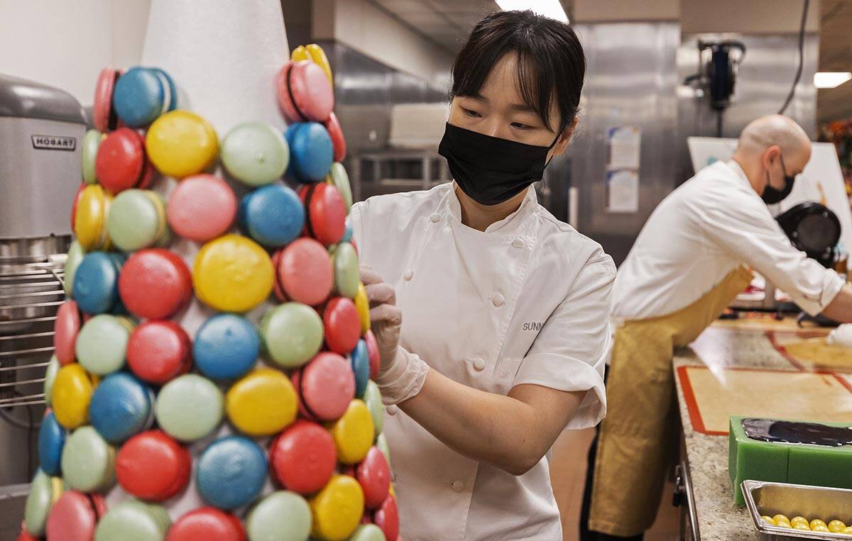 Assistant executive pastry chef Sunny Lee, left, uses icing to apply macaroons to a decorative ...