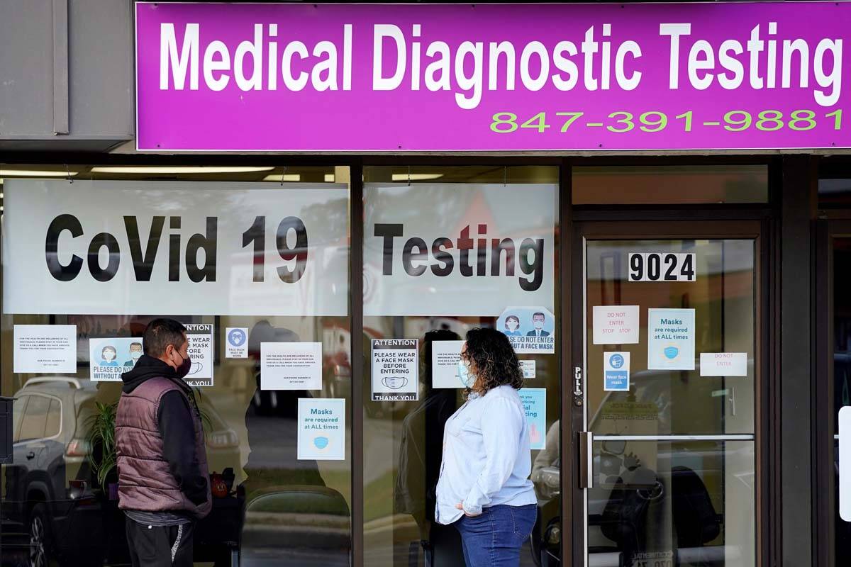 In this Oct. 21, 2020, file photo, an Exam Corp Lab employee, right, wears a mask as she talks ...