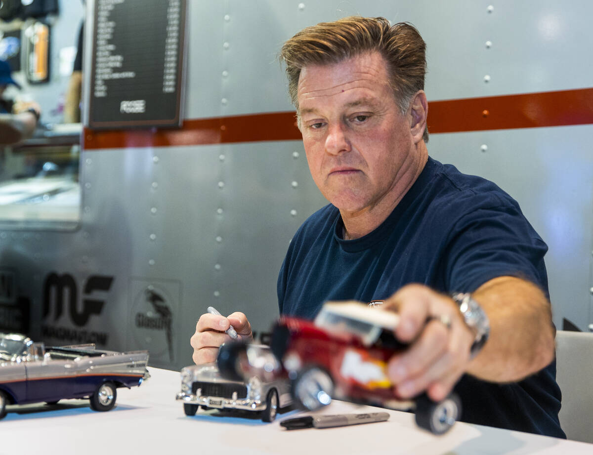 Chip Foose signs autographs on a model car at his display during SEMA at the Las Vegas Conventi ...