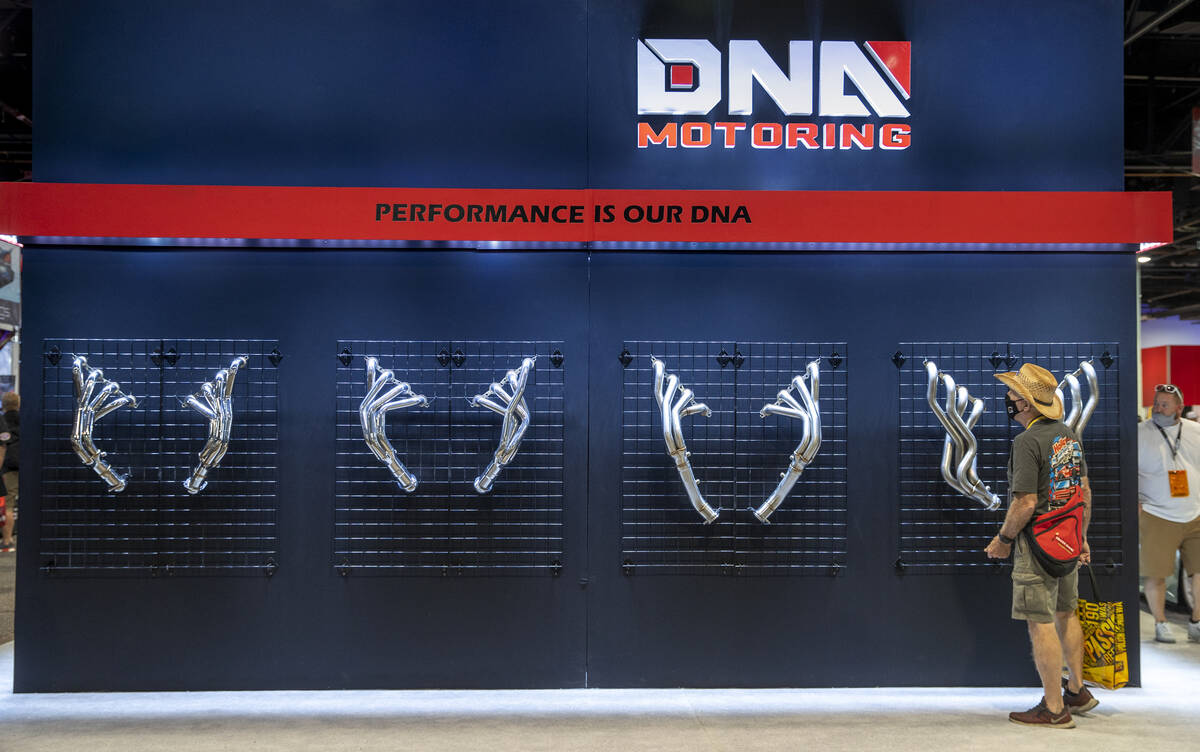 An attendee checks out some exhaust pipes on display from DNA Motoring during SEMA at the Las V ...