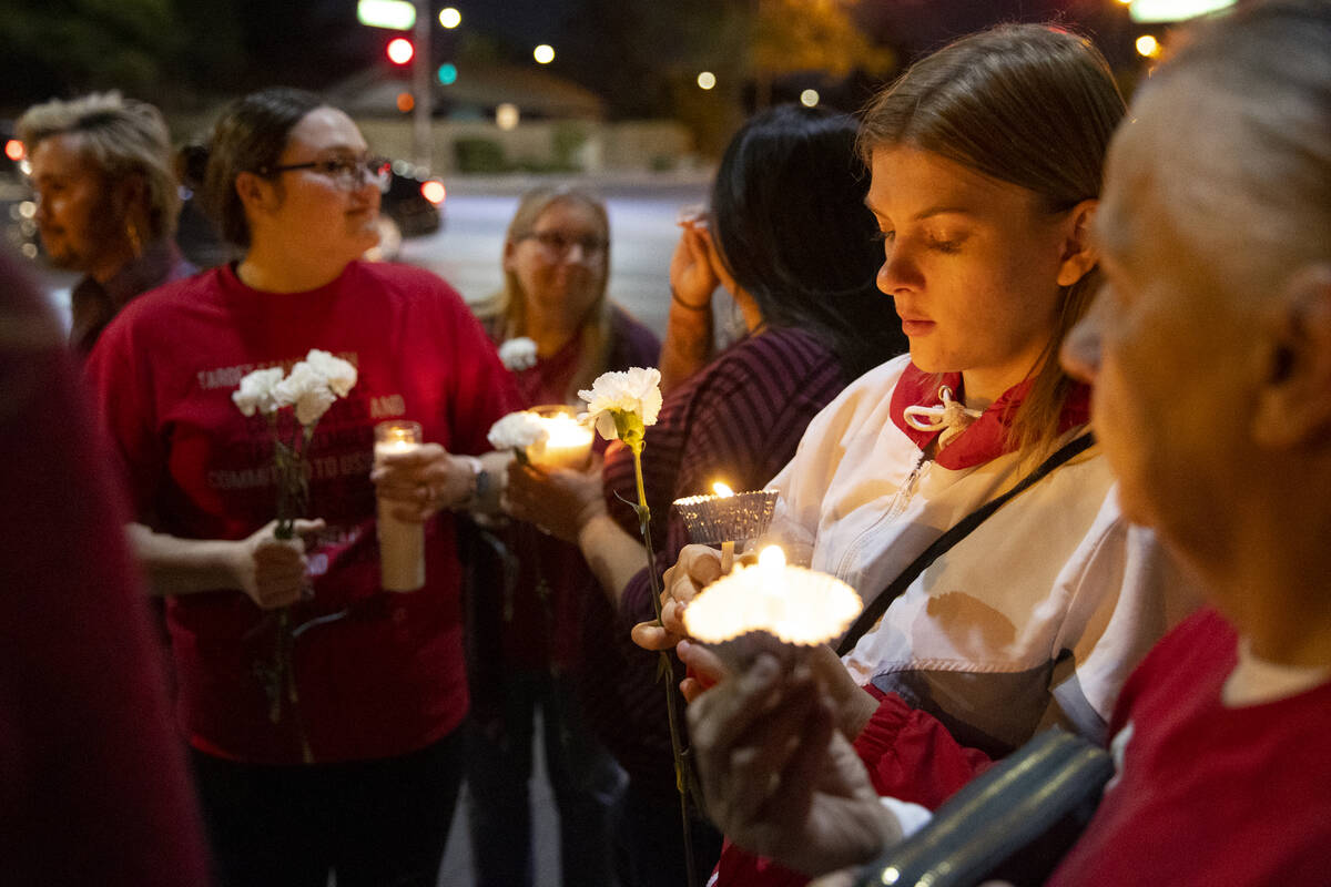 Jordan Vogl-Rees, center, holds a candle during a vigil for her coworker Tina Tintor and her do ...