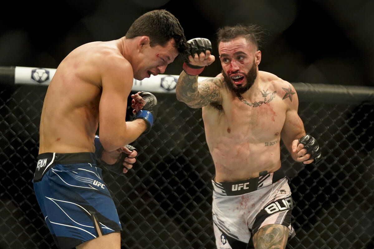 Shane Burgos, right, throws a punch against Billy Quarantillo during a featherweight mixed mart ...