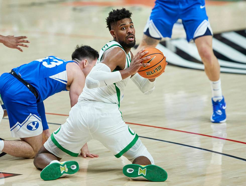 Oregon forward Quincy Guerrier, right, looks to pass the ball from next to BYU's Alex Barcello ...