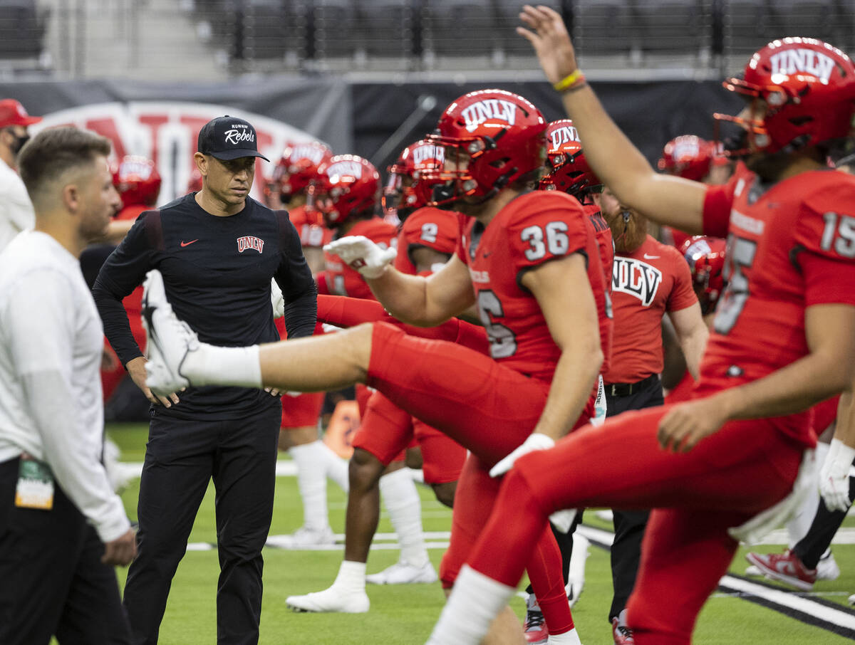 UNLV Rebels head coach Marcus Arroyo watches as his players stretch before an NCAA football gam ...
